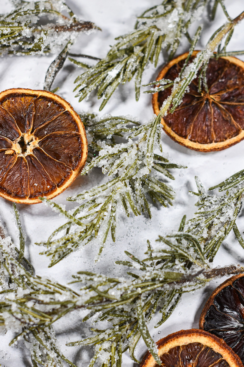 sugared rosemary and orange slices on a white surface