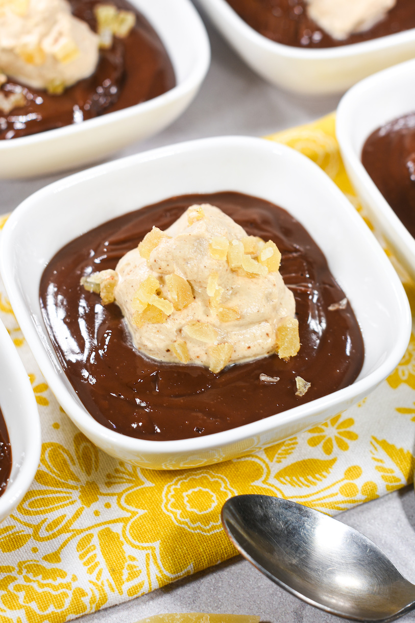 a dish of chai pudding with whipped cream and candied ginger