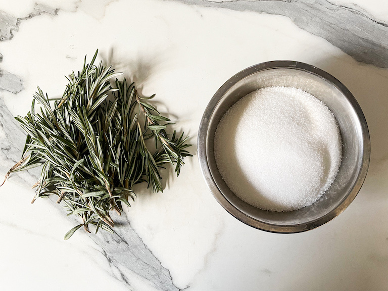 Sprigs of rosemary next to a dish of sugar