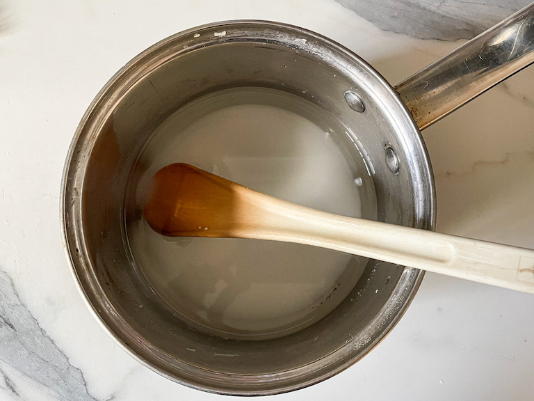 A pan with sugar, water, and a spoon