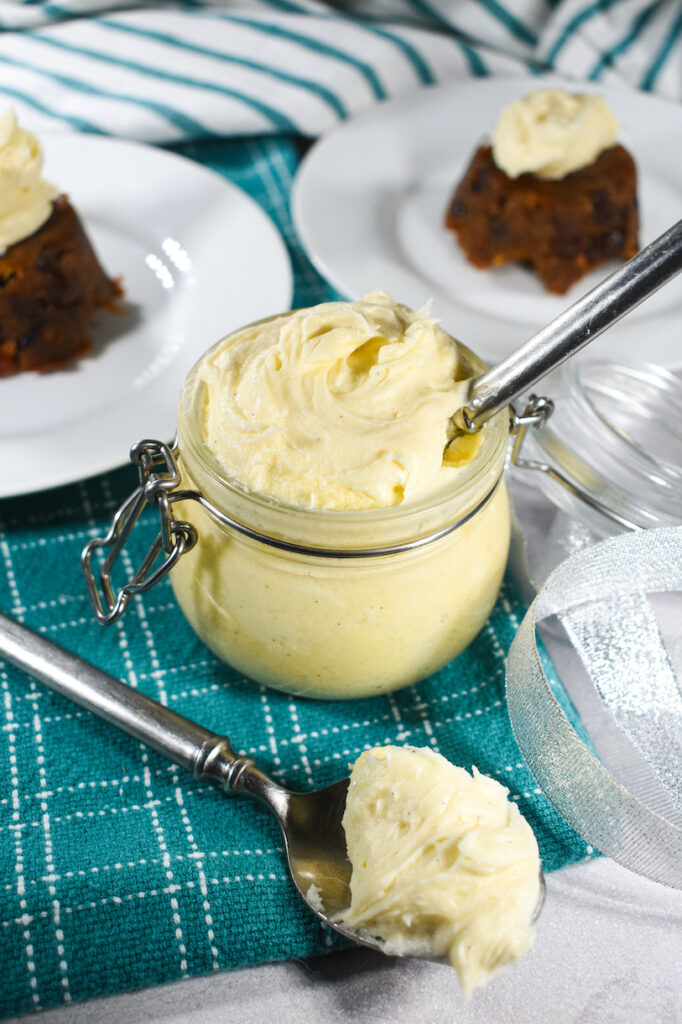 a small jar of brandy butter with christmas puddings