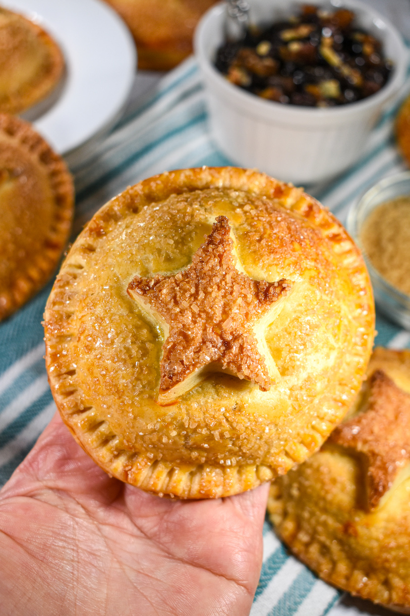 A hand holding a mince pie hand pie with a pastry star on top