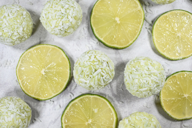 Green truffles for Saint Patrick's Day, arranged on a white surface with slices of fresh lime