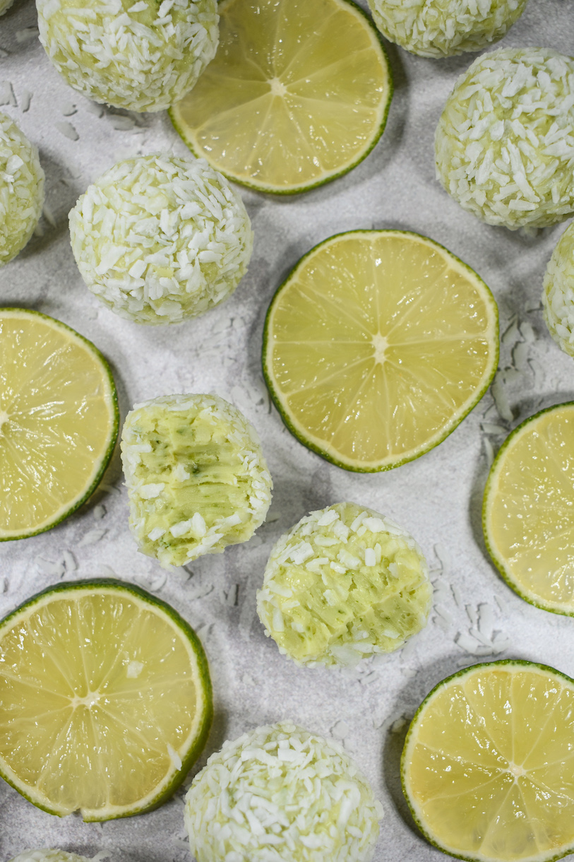 Green truffles and lime slices arranged on a white surface