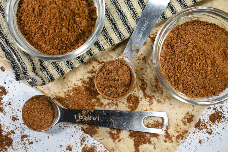 Homemade mixed spice in dishes and spoons, on a sheet of brown parchment