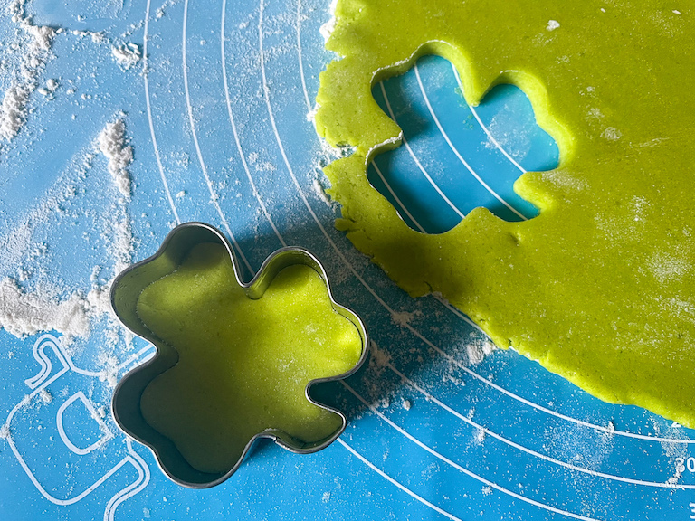 Cutting green dough with a shamrock shaped cookie cutter