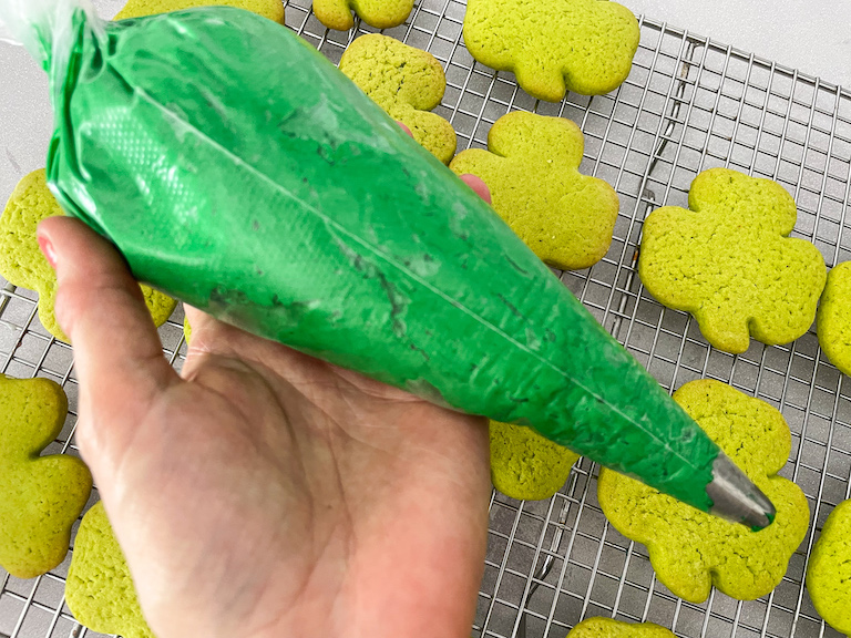 Hand holding a piping bag of green buttercream