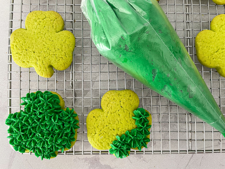 Piping decorations on green shamrock cookies