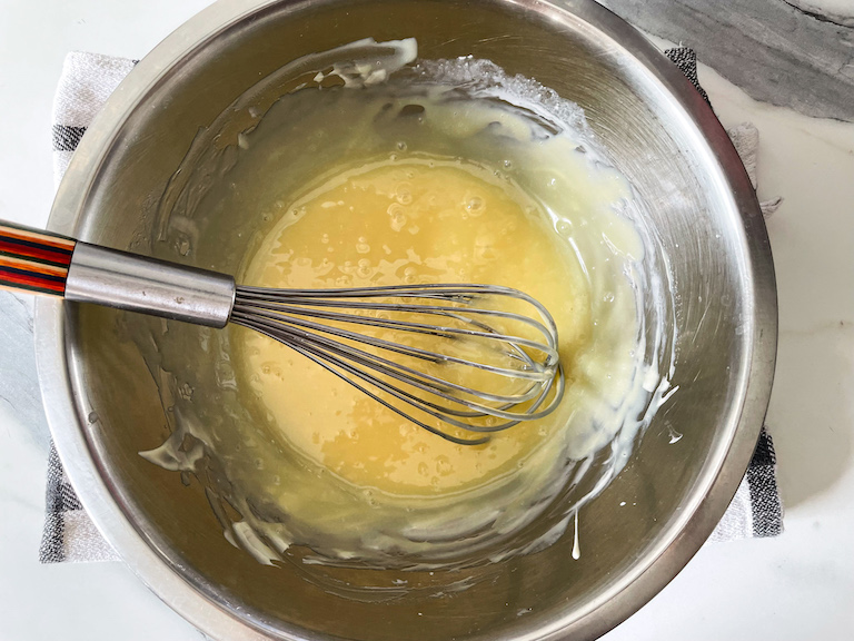 Melted white chocolate in a bowl with a whisk