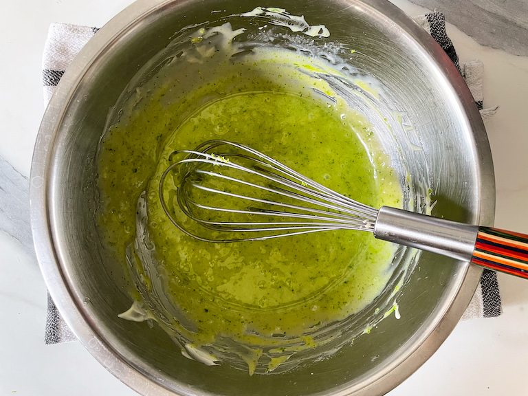 Lime and white chocolate ganache in a bowl with a whisk