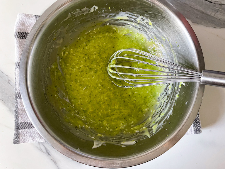 Lime green ganache in a bowl with a whisk