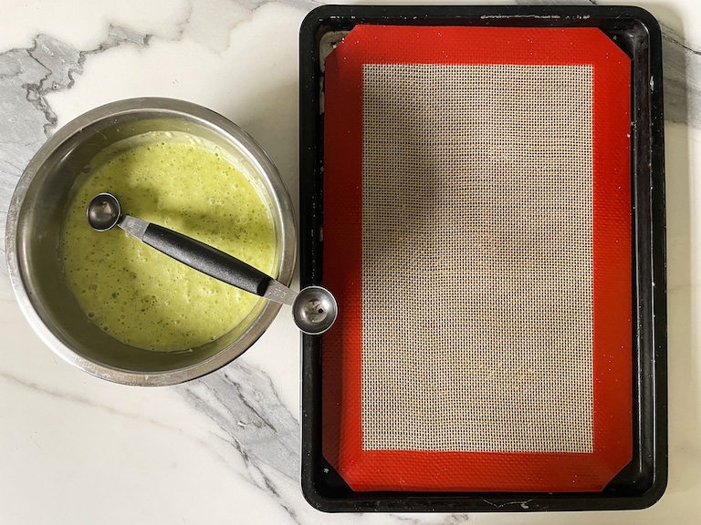 Bowl of green ganache, melon baller, and tray