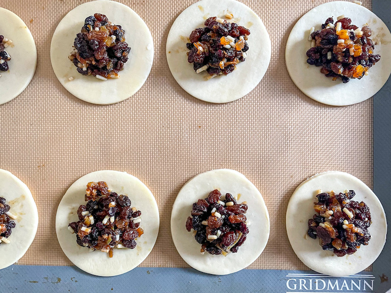 Scooping mince on top of discs of pastry for mincemeat hand pies