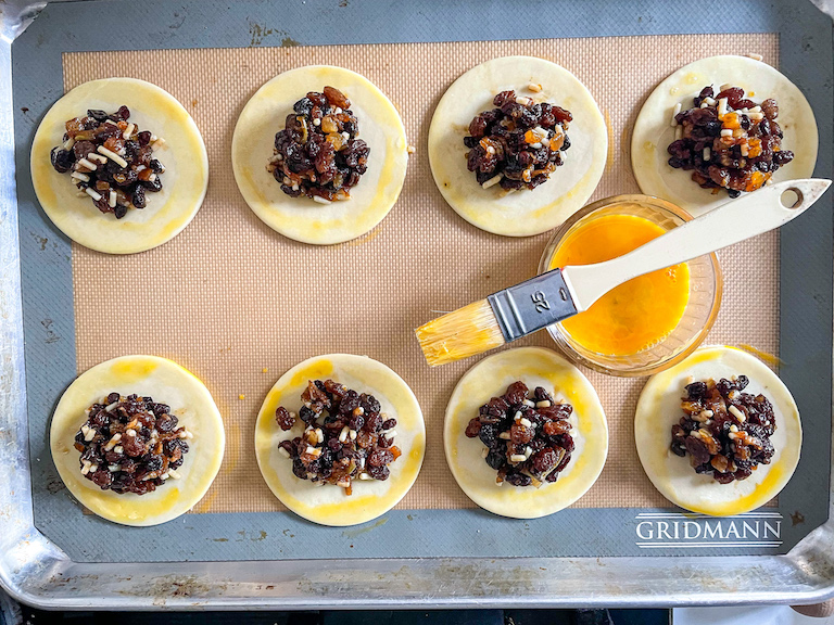 Pastry brush egg washing mincemeat hand pies before baking