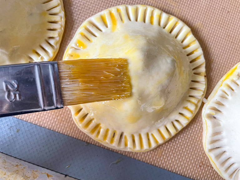 Brushing egg wash on a mincemeat hand pie