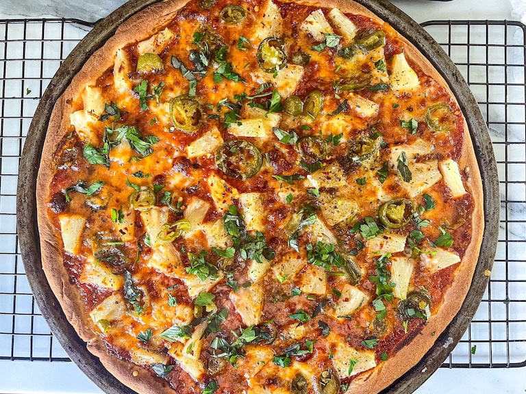 Jalpeño and pineapple pizza on a wire rack