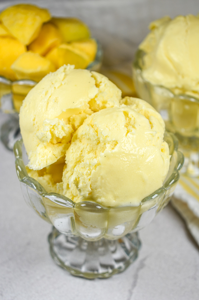 A glass dish with scoops of creamy mango ice cream