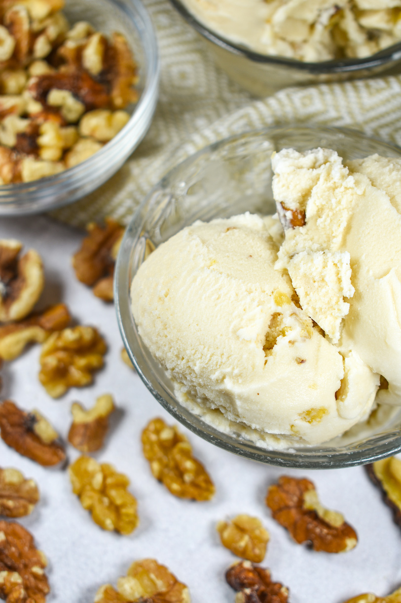 A dish of maple ice cream surrounded by walnuts