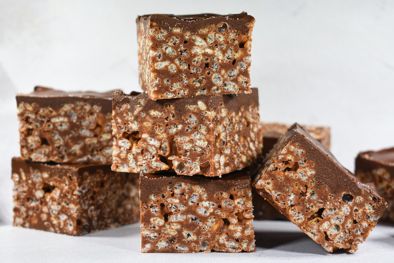 A stack of krispie treats with chocolate ganache, arranged on a white surface