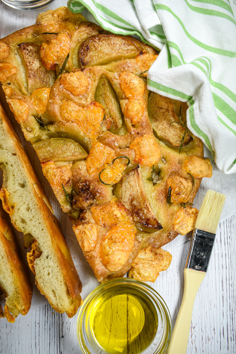 A loaf of cheese and apple focaccia and a dish of olive oil