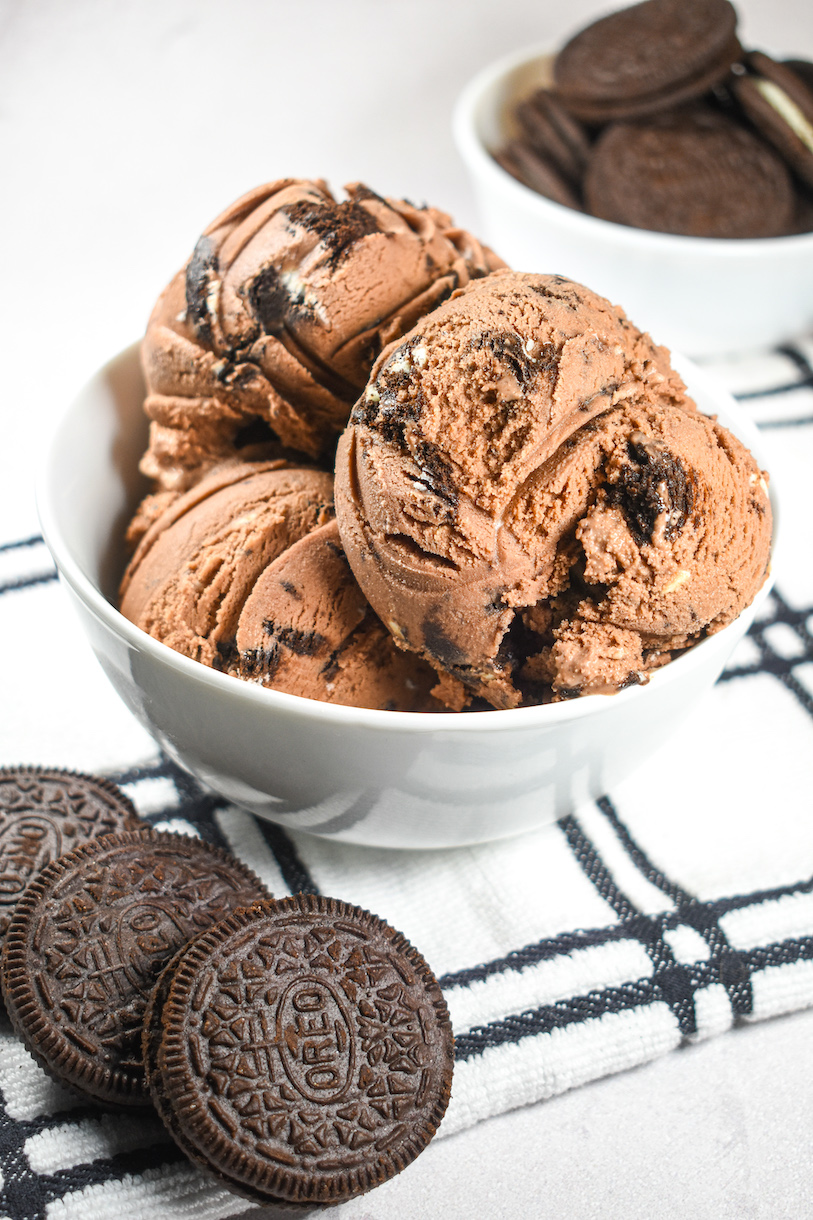 A bowl of Oreo ice cream and Oreo cookies arranged on a white plaid tea towel