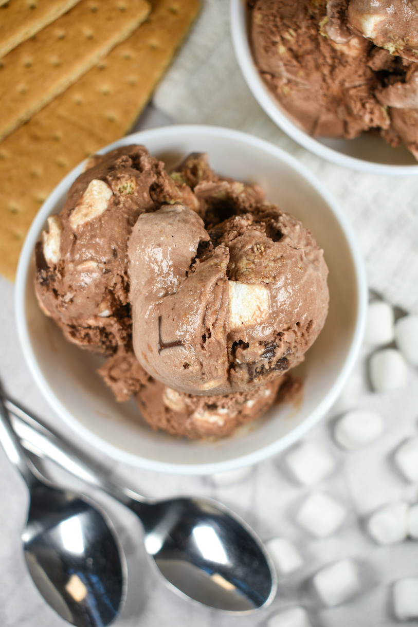 Dishes of homemade s'mores ice cream, spoons, marshmallows, and graham crackers