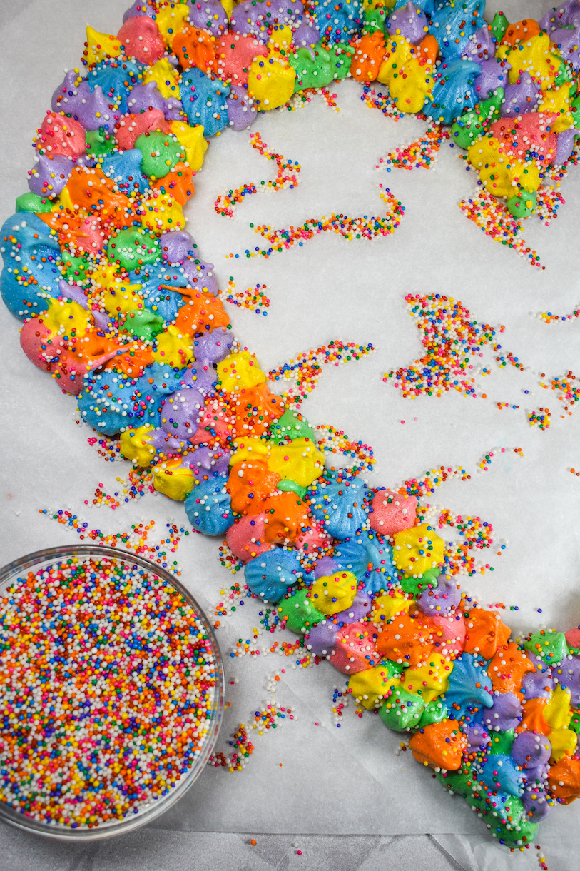 Piped meringue wreath and a dish of sprinkles