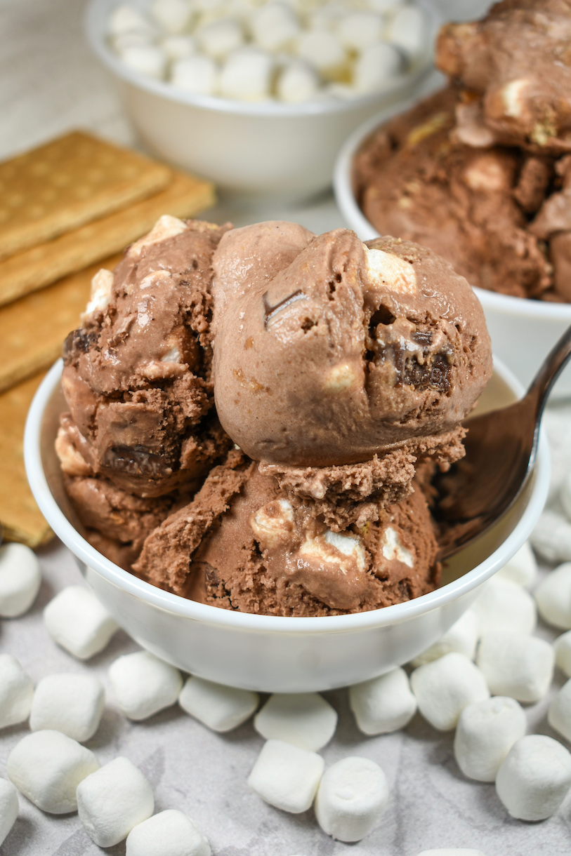 Bowl of smores ice cream surrounded by graham crackers and marshmallows