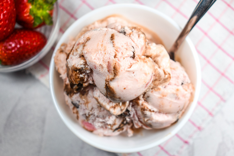 A dish of chocolate strawberry ice cream and dish of red strawberries