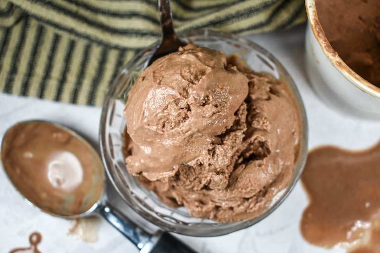 A dish of chocolate hazelnut ice cream and an ice cream scoop