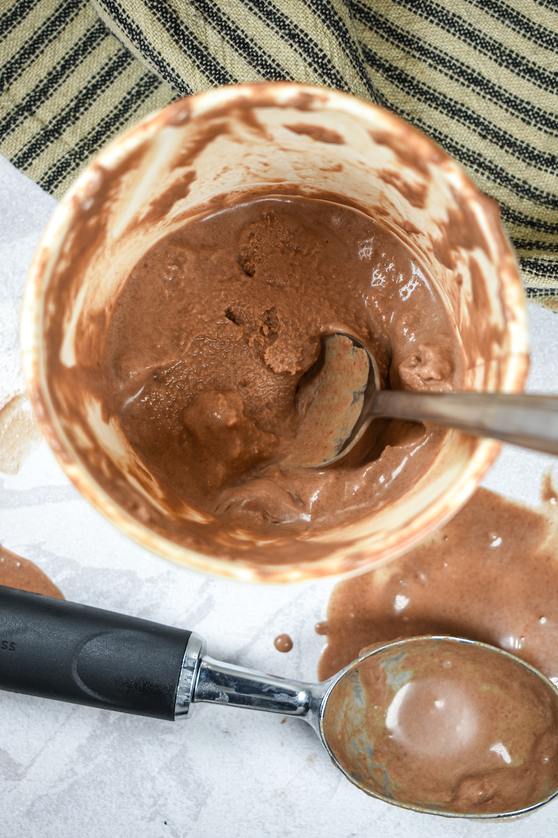 A half eaten pint of Nutella ice cream, spoon, and ice cream scoop