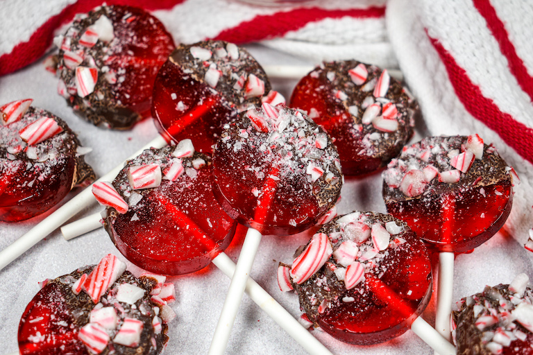 Chocolate dipped peppermint lollipops on a red and white striped towel