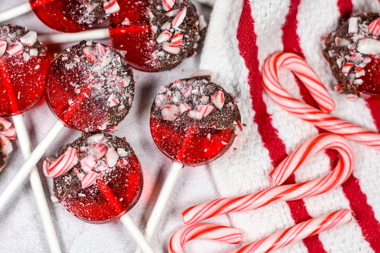 Peppermint lollipops and candy canes on a striped tea towel