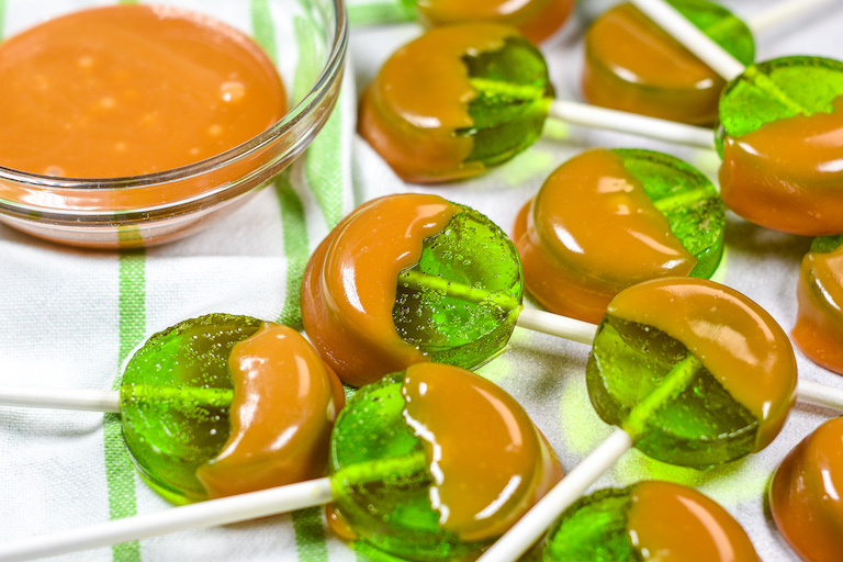 Caramel apple lollipops on a green and white striped towel