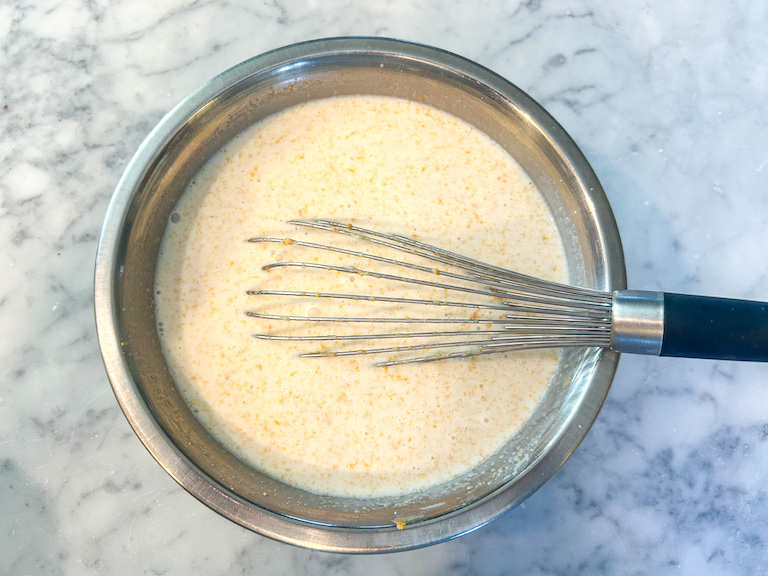 Cream, peanut butter, and a whisk in a metal bowl