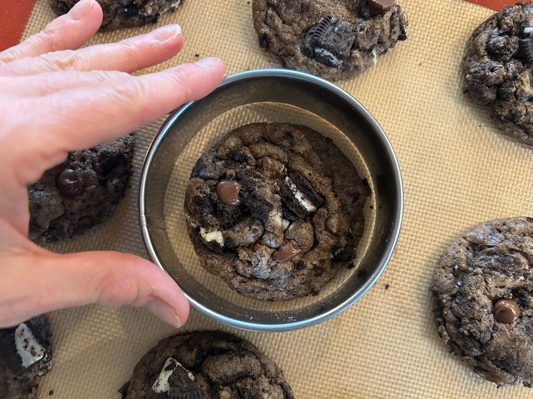 Hand reshaping cookies with a round metal cutter