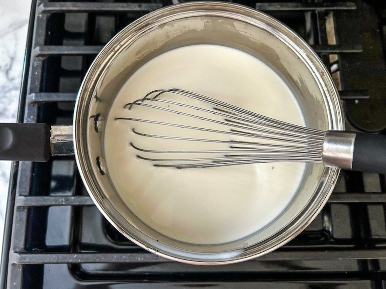 Cream and milk in a pan with a whisk