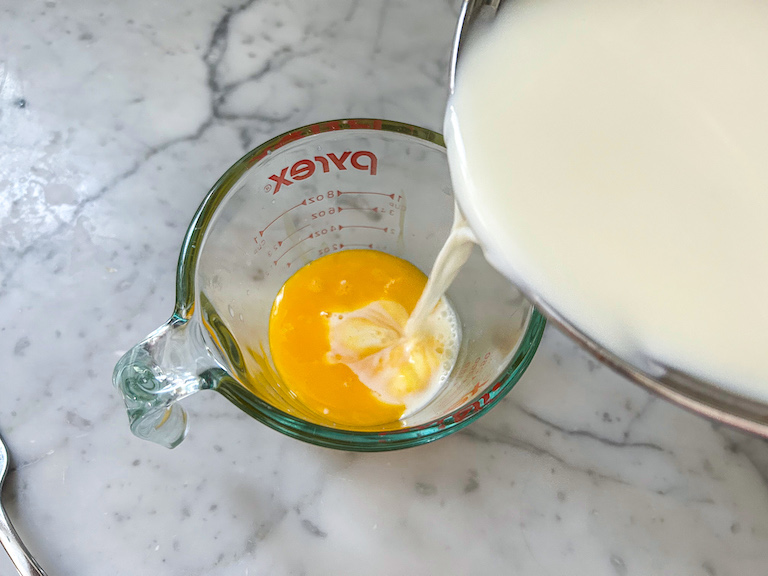 pouring hot cream into egg yolks