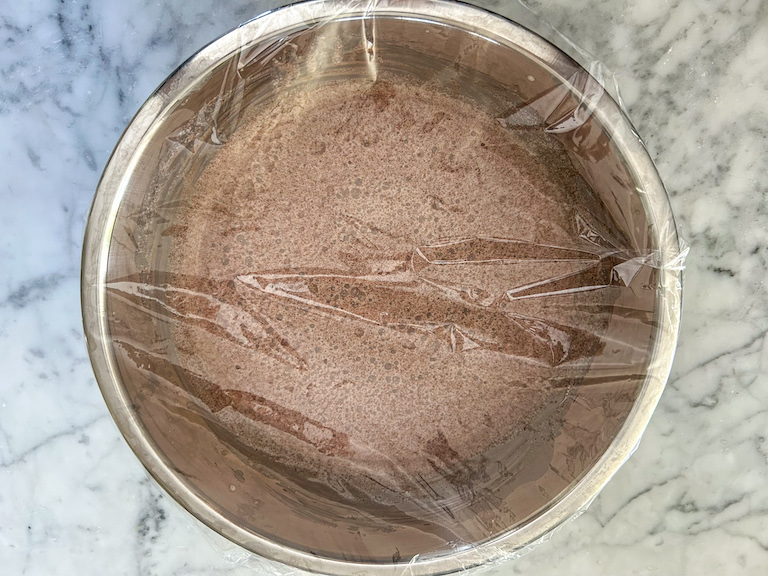 Chocolate ice cream mixture in a bowl covered in plastic wrap