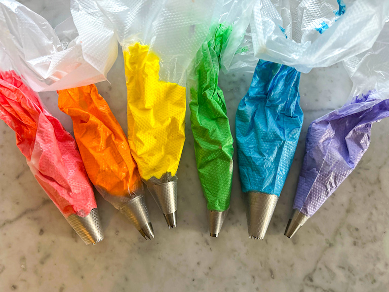 Rainbow colored meringues in piping bags