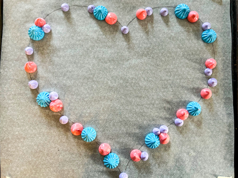 Pink, blue, and purple meringue piped in a heart shaped wreath