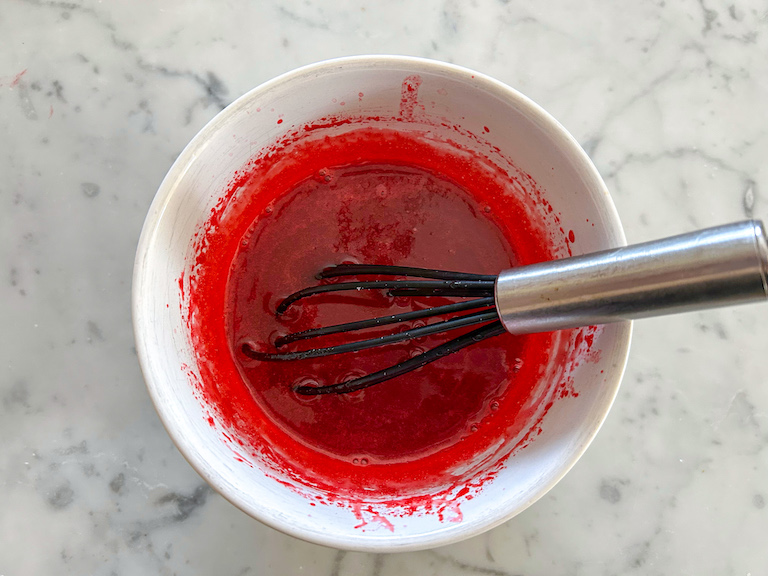 Red gelatin in bowl with whisk