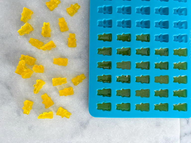 Silicone mold and homemade yellow gummy bears on a white surface