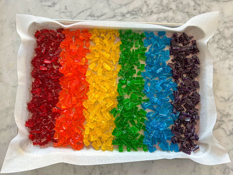 A tray of homemade gummy bears arranged in a rainbow pattern