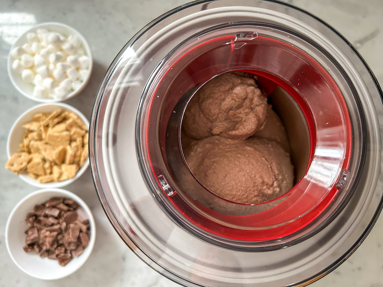 Ice cream maker and dishes of marshmallows, graham crackers, and chopped chocolate