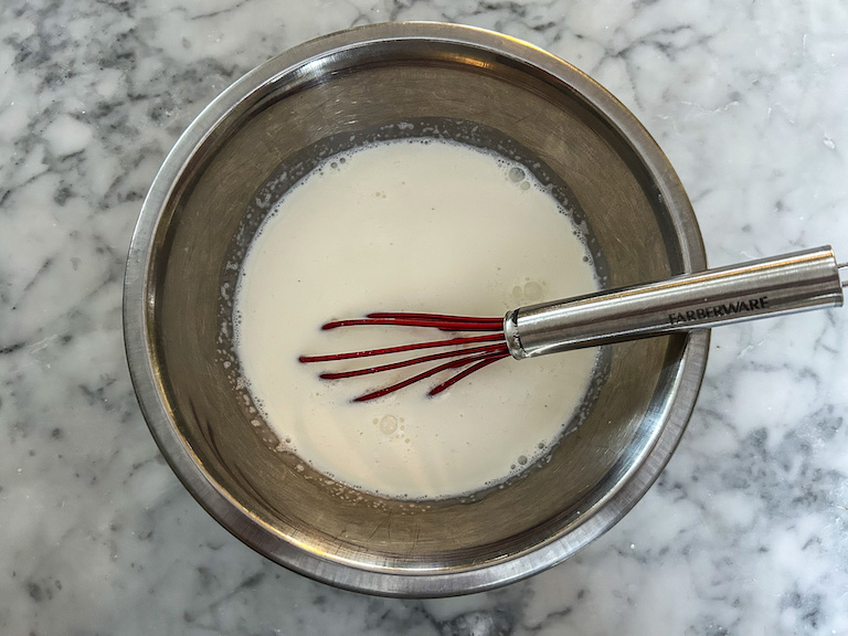 A bowl of milk with a whisk