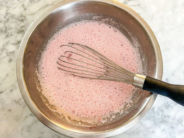 Whisking bowl of strawberry ice cream base