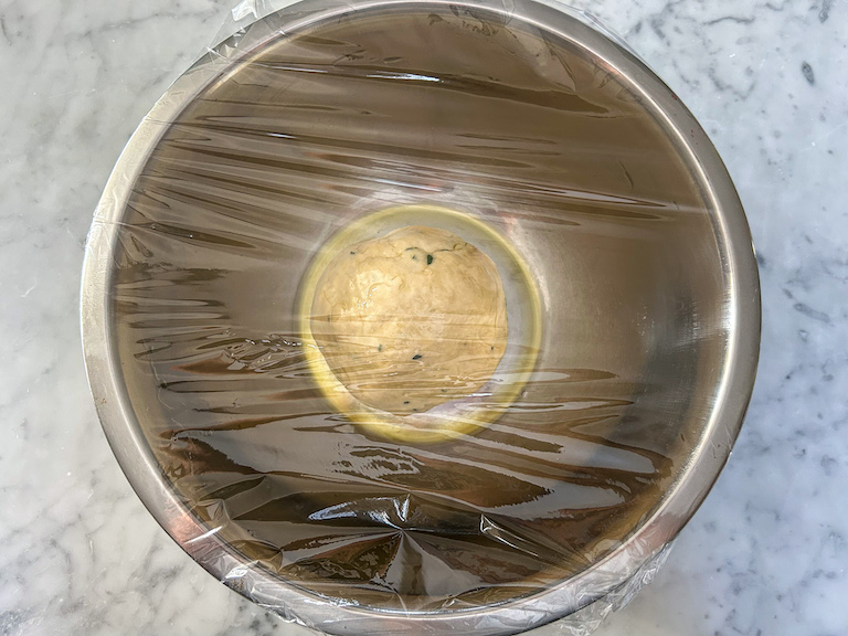 Bowl of bread dough covered with plastic wrap