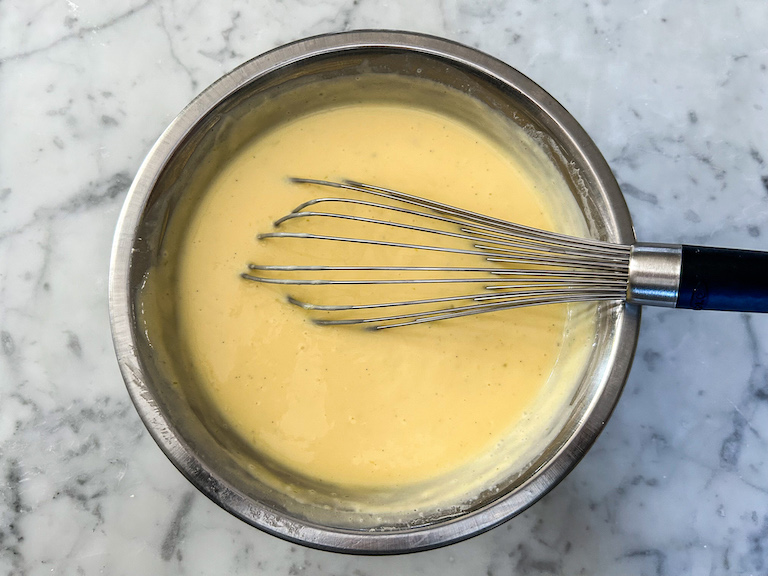 Mango ice cream base in a bowl with a whisk