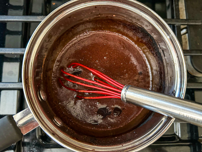 Saucepan of fudge sauce and a whisk